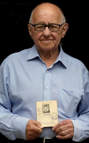 Holocaust survivor Zigi Shipper holds his entry passport from 1946 at his home