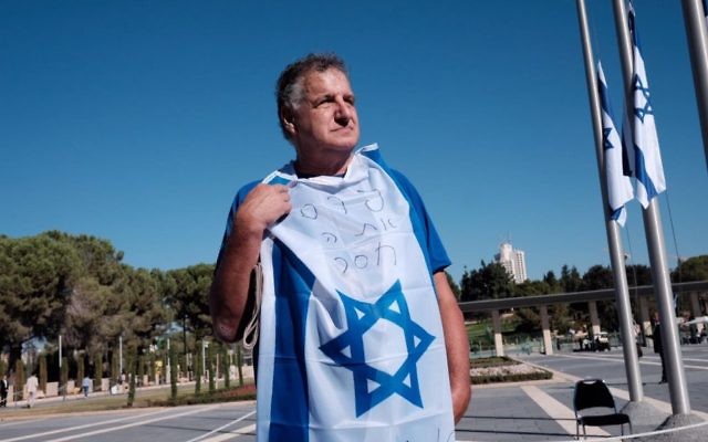 A mourner, draped in the Israeli flag, pays his own personal tribute to Peres