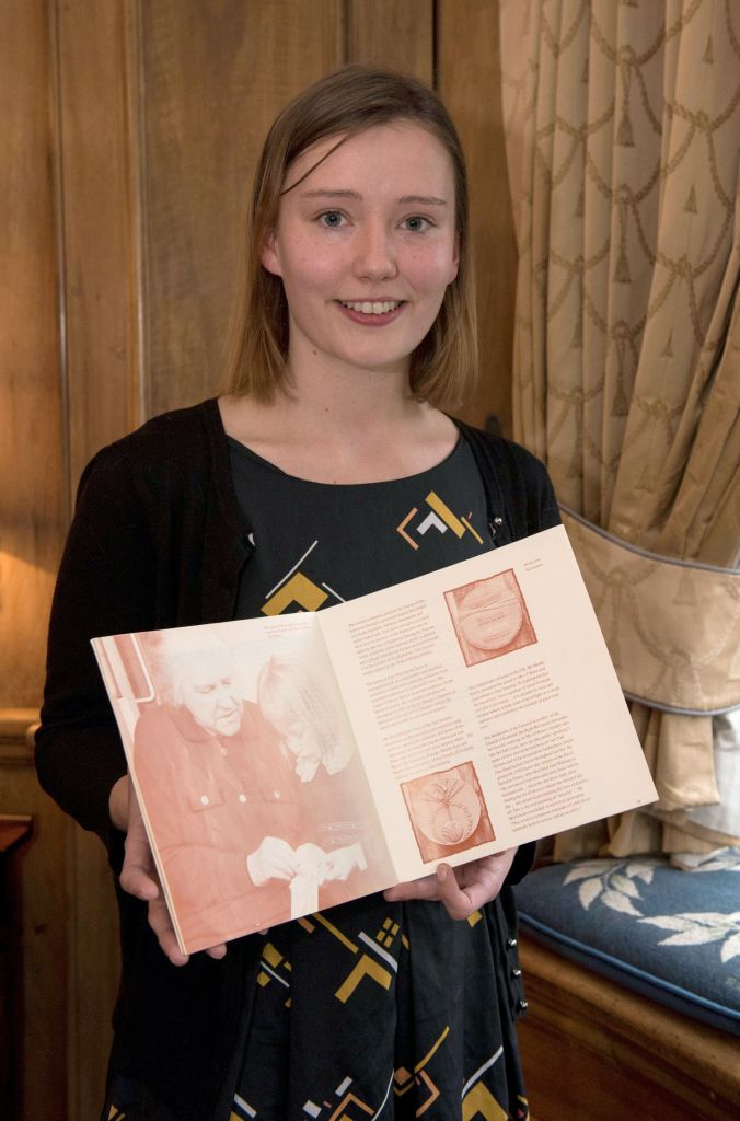 Caitriona Topping with book on Jane Haining in which she is pictured as a four year old with Agnes O'Brien and Jane Haining's medal. (Photo credit: Andrew O'Brien/Church of Scotland/PA) 