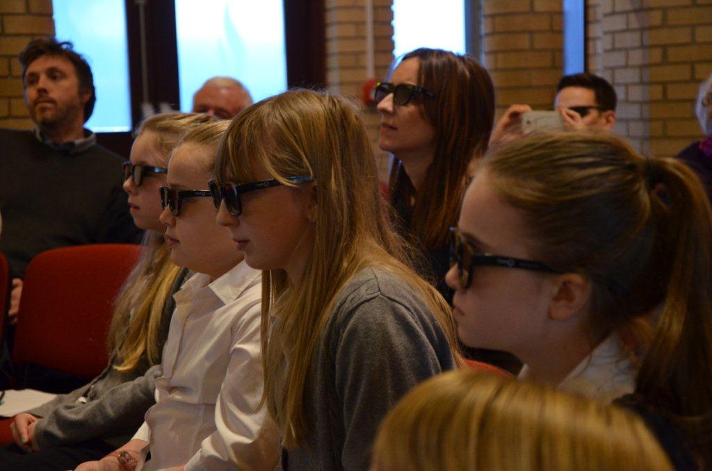 Students with 3D glasses, listening to survivors speak 