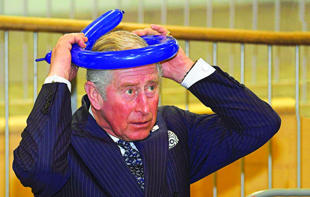 Prince Charles fashioning a balloon crown during his visit to the school 