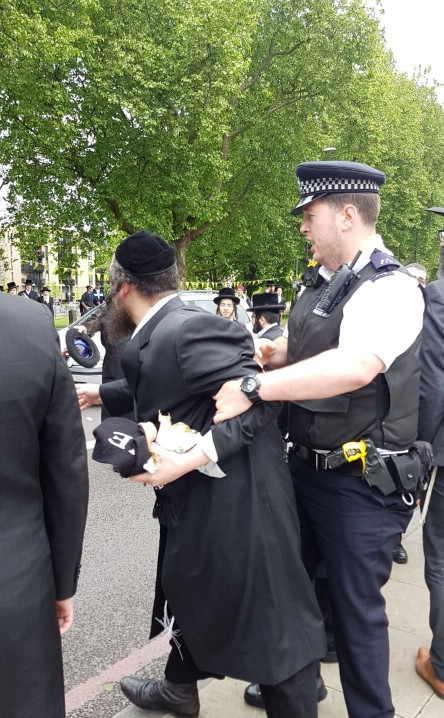 Police detain a member of the hassidic community during scuffles 