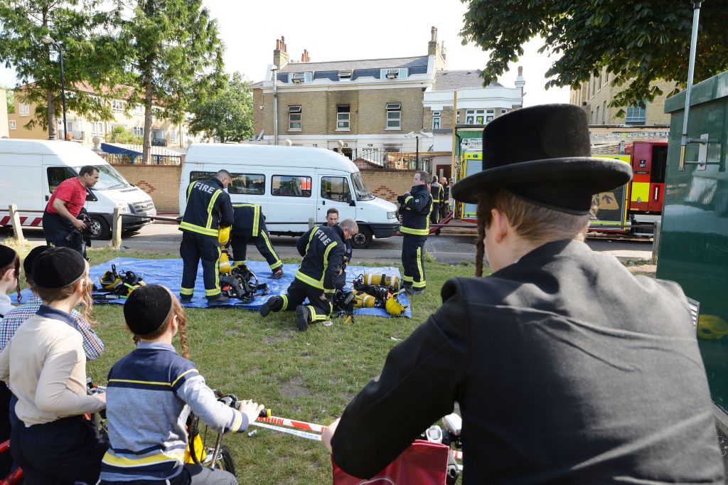 Jewish members of the public watch firefighters outside a school in Craven Walk in Hackney, east London, after a fire broke out shortly before midnight on Tuesday. Photo credit: John Stillwell/PA Wire 
