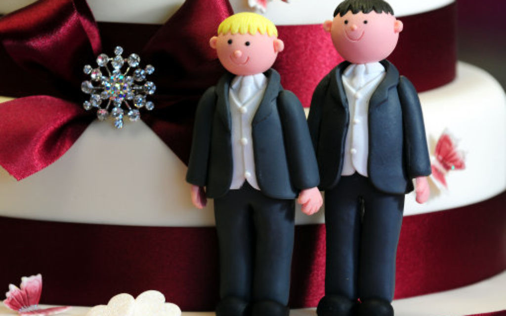 Two grooms decorating a wedding cake.