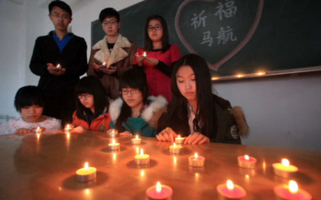 College students light candles to pray for the missing passengers