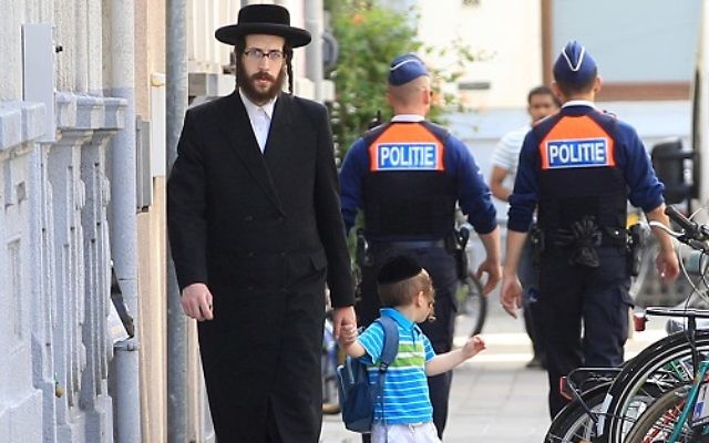 An orthodox Jew and a boy pass two police officers in Antwerp, Belgium,   2014.  (AP Photo/Yves Logghe)