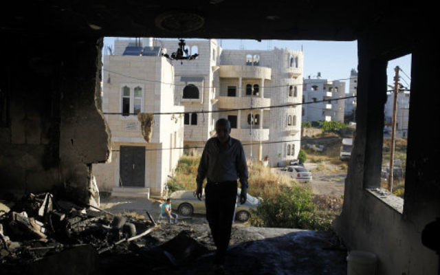 A Palestinian inspects the damaged family home of Amer Abu Aisheh, one of two Palestinians identified  as suspects in the killing of the three Israeli teenagers.