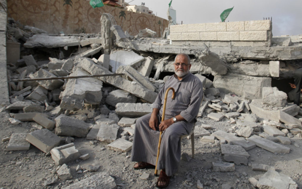 A Palestinian sits in the rubble of the house of Hussam Kawasma, one of three Palestinians identified by Israel as suspects in the killing of the three kidnapped Israeli teenagers.