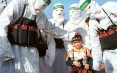 Hamas terrorists surround a child dressed as a suicide bomber. Hamas terrorists surround a child dressed as a suicide bomber.
