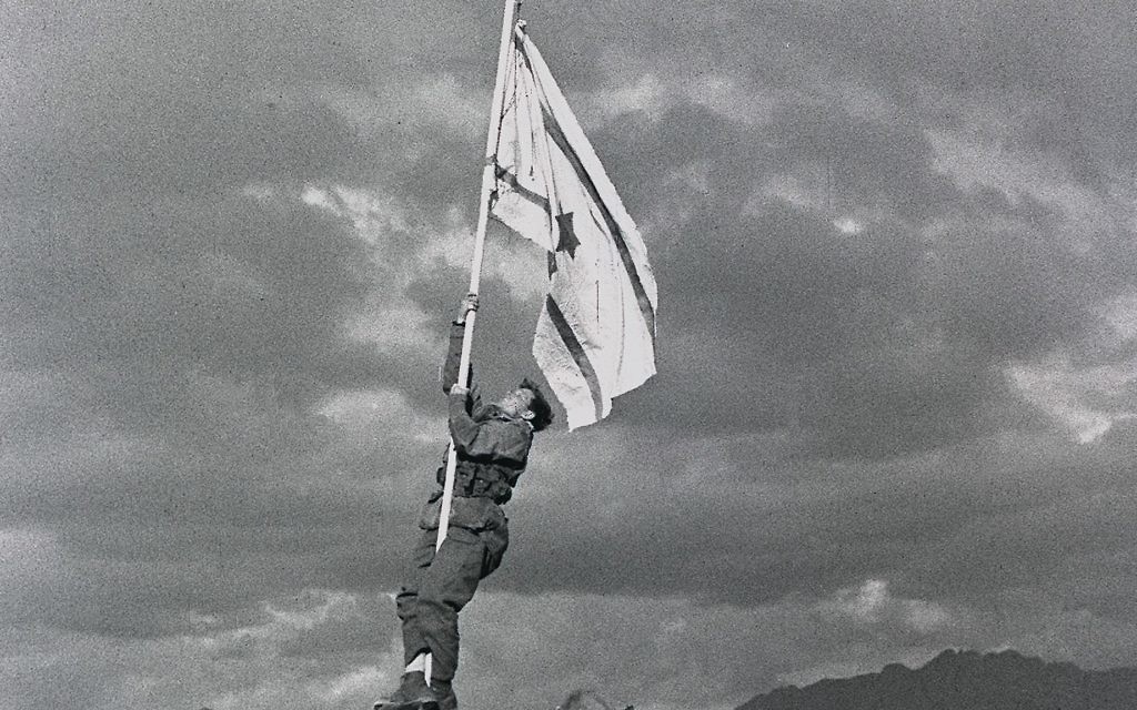 Captain Avraham "Bren" Adan raising the Ink Flag at Umm Rashrash (a site now in Eilat), marking the end of the war.