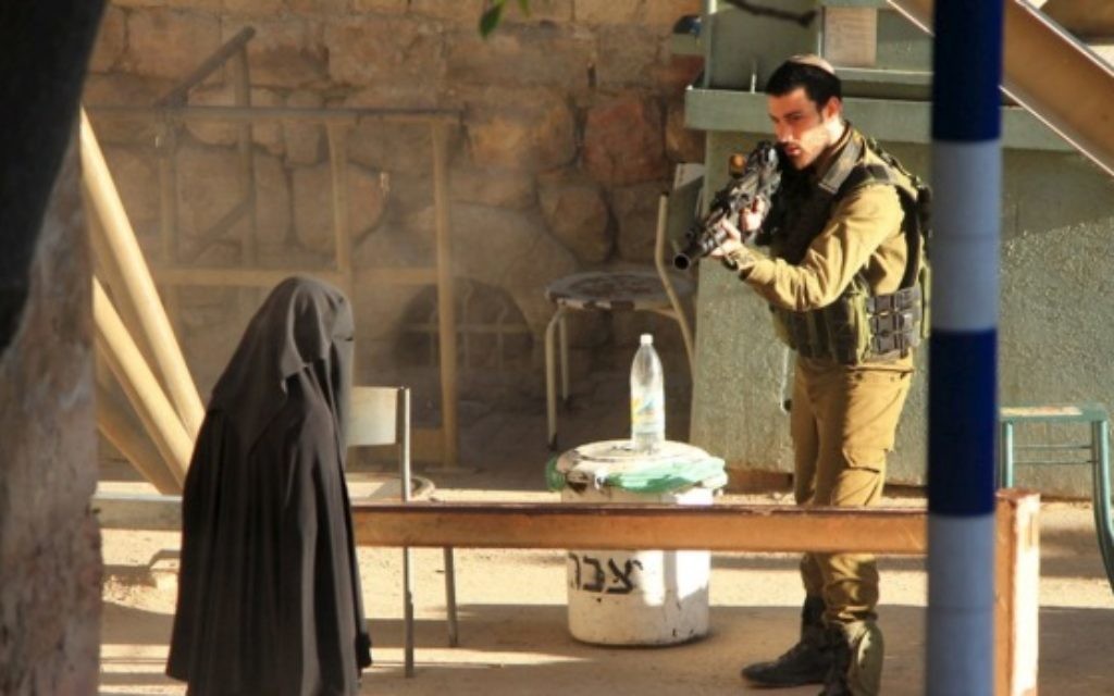 An Israeli soldier aims his rifle at an 18-year-old Palestinian student.