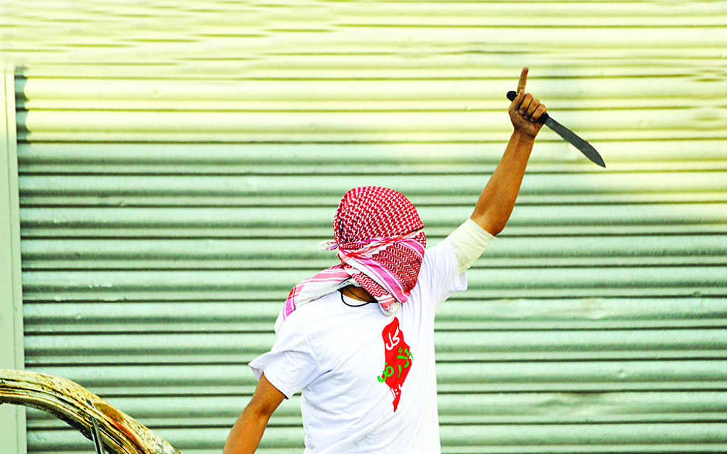 A Palestinian demonstrator raises a knife, during clashes with Israeli police, in Shuafat refugee camp in Jerusalem,, Oct. 2015.  (AP Photo/Mahmoud Illean)