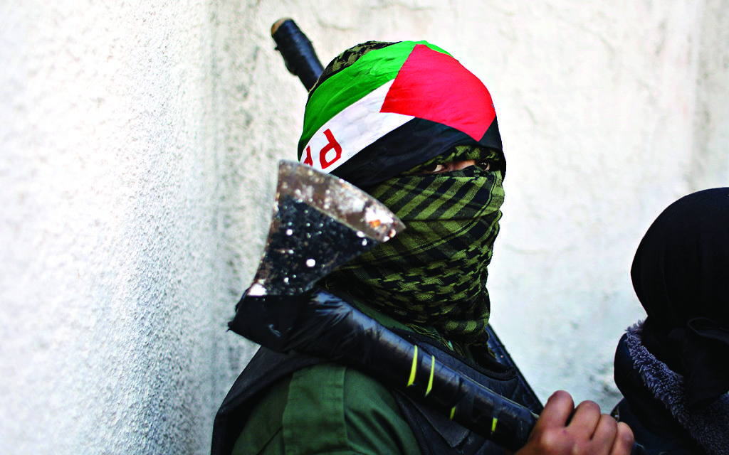 A masked Palestinian youth carries an axe in the West Bank (AP Photo/Nasser Nasser)