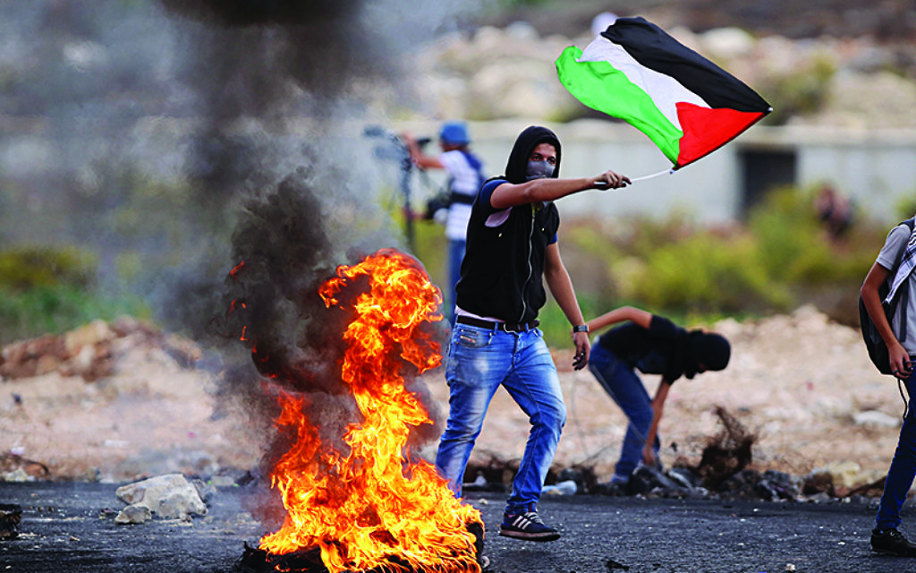 A Palestinian protester holds national flag during clashes with Israeli soldiers, in Beit El, on the outskirts of the West Bank city of Ramallah, on Oct. 18, 2015.   (Xinhua)