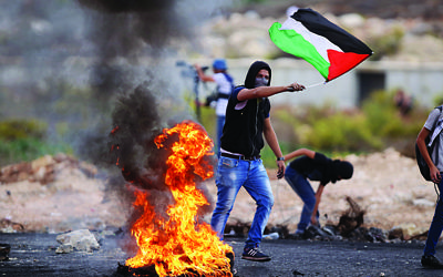A Palestinian protester holds national flag during clashes with Israeli soldiers, in Beit El, on the outskirts of the West Bank city of Ramallah, on Oct. 18, 2015.   (Xinhua)