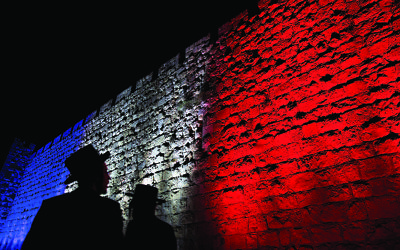 Two Orthodox Jews look at Jerusalem's Old City walls illuminated by the colours of the French national flag in solidarity with France after attacks in Paris, in Jerusalem, Sunday, Nov. 15, 2015. (AP Photo/Ariel Schalit)