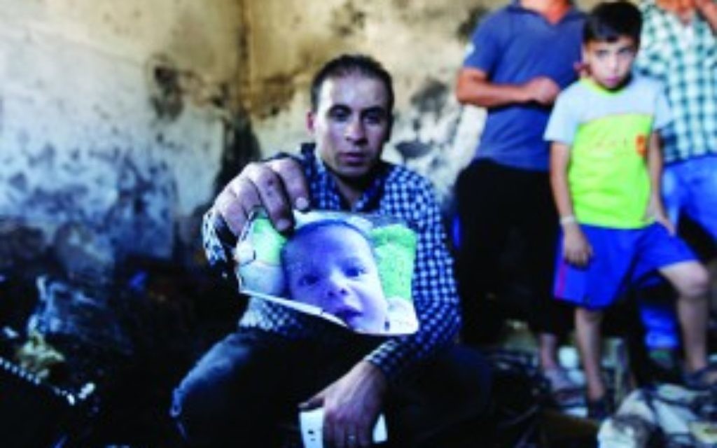 A relative holds up a photo of a one-and-a-half year old boy, Ali Dawabsheh, in a house that had been torched in a suspected attack by Jewish settlers in Duma village near the West Bank city of Nablus, Friday, July 31, 2015