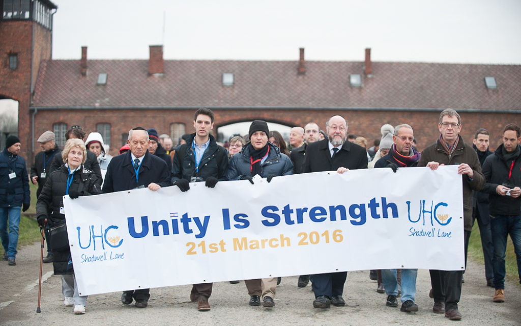 Unity is Strength banner held up outside the gates of the notorious death camp. Chief Rabbi Mirvis is on the