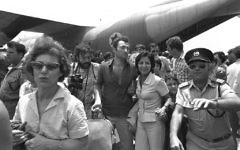 A-police-officer-clears-the-way-for-rescued-Air-France-hostages-returning-from-Entebbe-Airport. A-police-officer-clears-the-way-for-rescued-Air-France-hostages-returning-from-Entebbe-Airport.