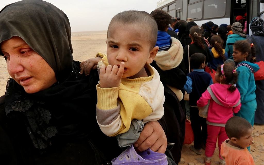 Syrian refugees wait in line to get on a bus after crossing into Jordan at the Hadalat reception area on the Syrian-Jordanian border.