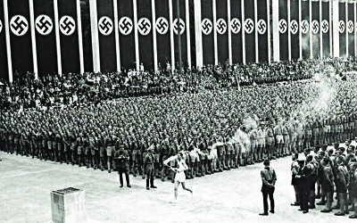 The Olympic Torch-bearer runs through the stadium at the 1936 Berlin Games