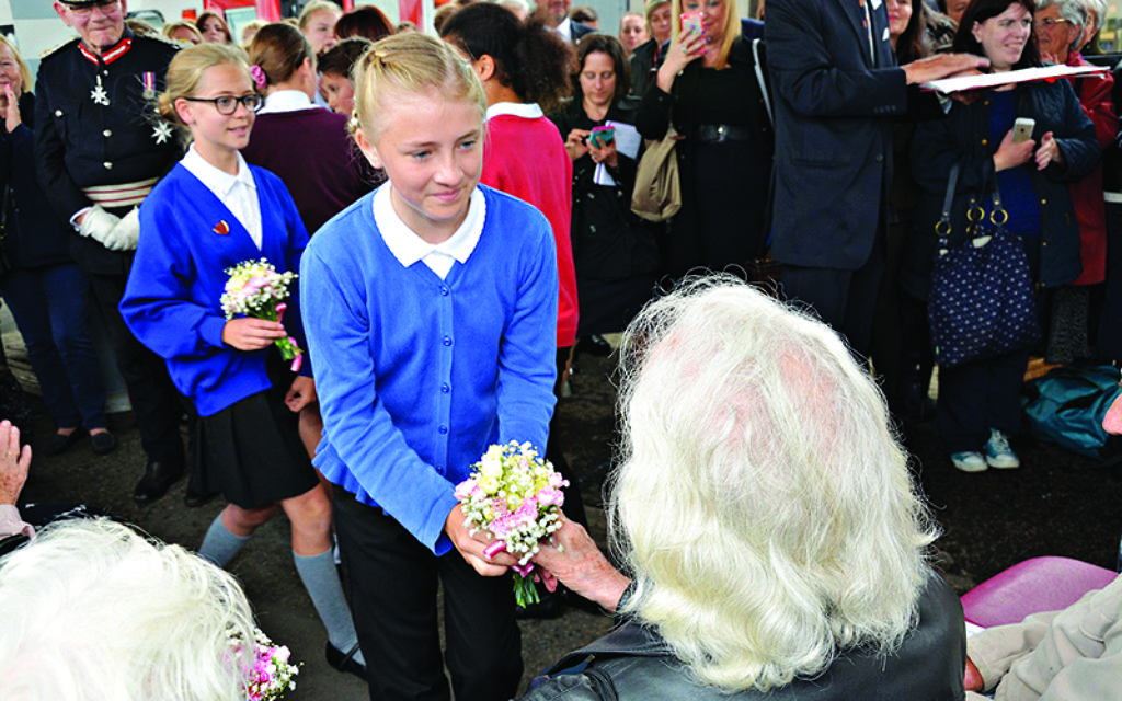 A girl hands a posy to a ‘Kind’.