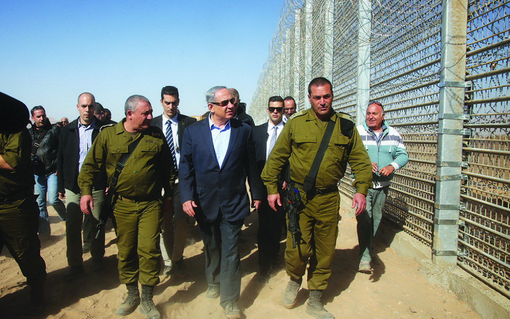 Israeli Prime Minister Benjamin Netanyahu walks with IDF Chief of Staff Gadi Eizenkott, left, as they visit the construction work on the fence between Israel and Jordan Tuesday, Feb. 9, 2016. (Marc Israel Sellem, Jerusalem Post, Pool via AP)