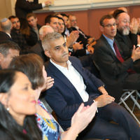 Sadiq Khan (centre) listening to a speaker