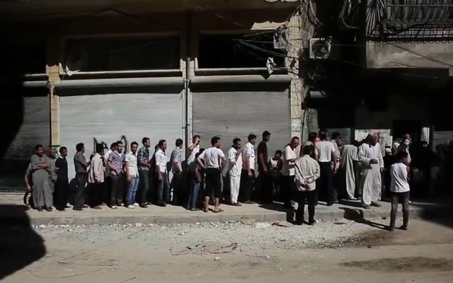 People of Aleppo waiting in a bread line during the civil war