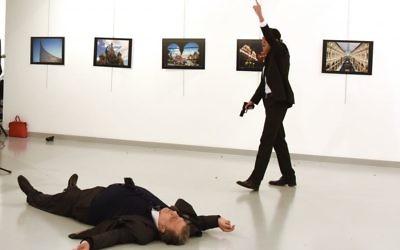 A man identified as Mevlut Mert Altintas stands over Andrei Karlov, the Russian Ambassador to Turkey, after shooting him at a photo gallery in Ankara, Turkey (Press Association)