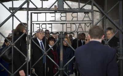 Mike Pence looks through the camp gates which reads "Arbeit macht frei" - a German phrase meaning "work sets you free"