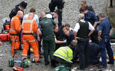 Conservative MP Tobias Ellwood (centre) helps emergency services attend to a police officer outside the Palace of Westminster, London, after a policeman was stabbed and his apparent attacker shot by officers in a major security incident at the Houses of Parliament. (Photo credit: Stefan Rousseau/PA Wire)