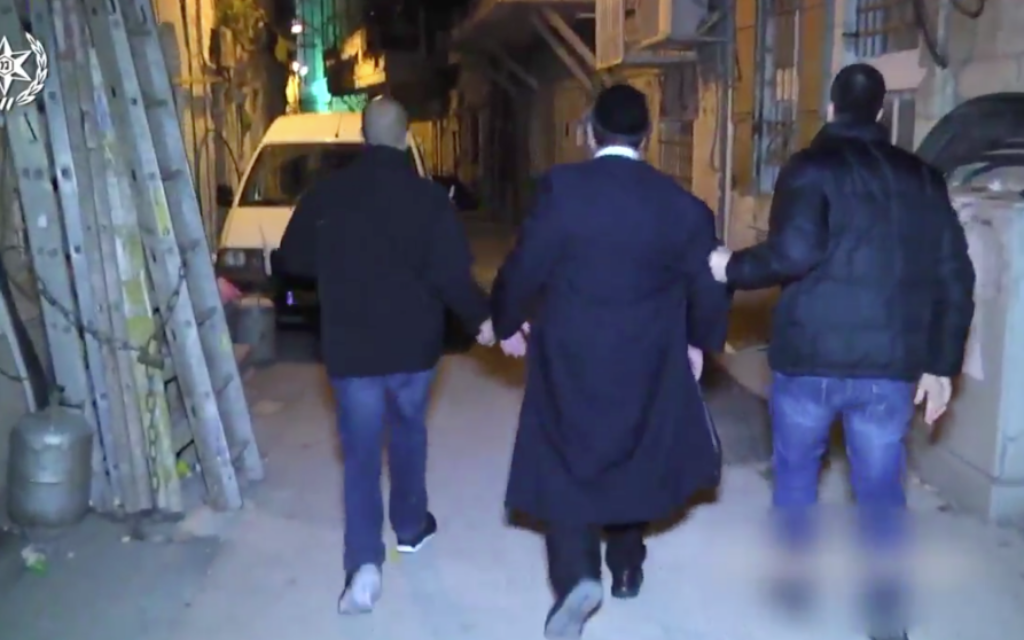 A Charedi man, handcuffed, being taken away by Israeli police
