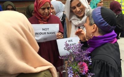 Rabbi Laura Janner-Klausner talking to Muslim women, holding signs that say 'Not in our Name'