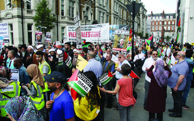 Pro-Palestinian supporters wave the Hezbollah flag, which features a rifle, on their march through central London