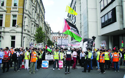 Pro-Palestinian supporters wave the Hezbollah flag, which features a rifle, on their march through central London
