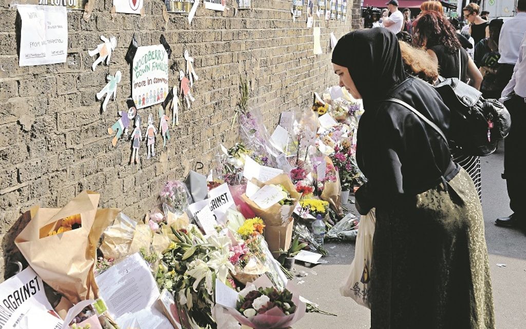 A woman leaves a floral tribute on Seven Sister Road close to Finsbury Park Mosque in north London, after a van was driven into pedestrians near the north London mosque, leaving one man dead and eight injured.