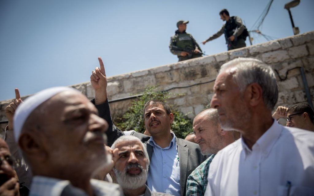 Palestinians pray as Israeli policemen guard during Friday prayers in the East Jerusalem, following a terror attack earlier that day. July 2017 

Photo by: JINIPIX