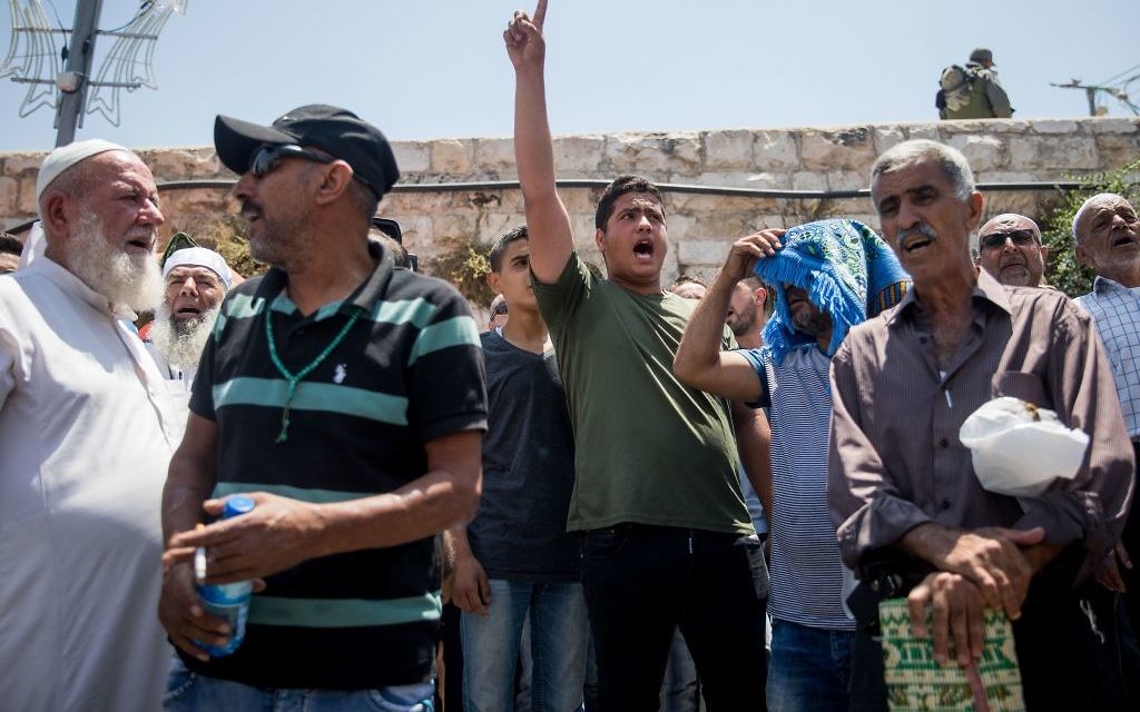 Palestinians pray as Israeli policemen guard during Friday prayers in the East Jerusalem, following a terror attack earlier that day. July 2017 

Photo by: JINIPIX