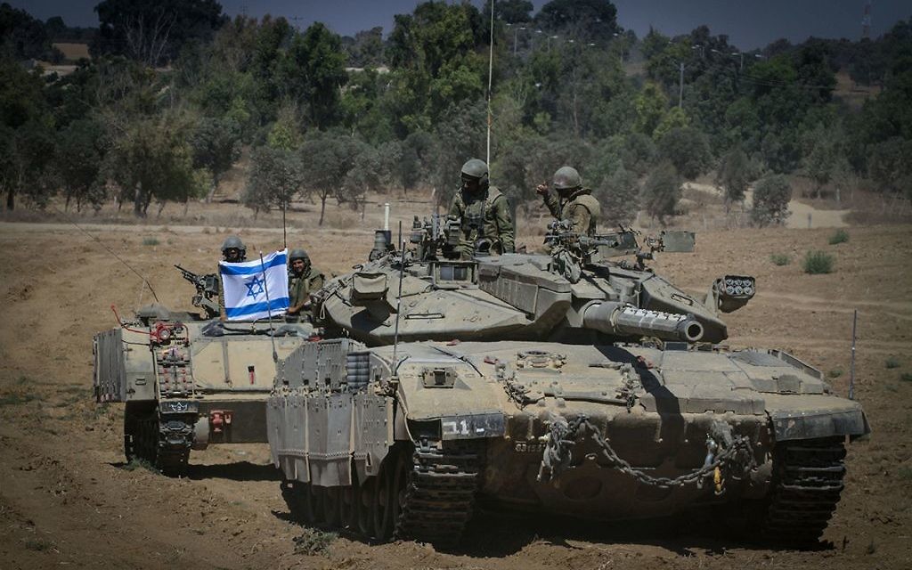 Israeli soldiers hold an Israeli flag on top of a tank