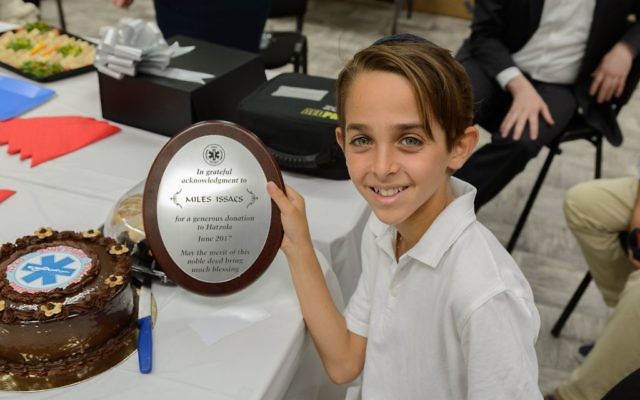 Miles Isaacs  with a plaque which says Hatzola offer a “grateful acknowledgment for a generous donation”.