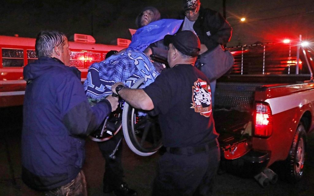 Rescue personnel help lower this wheelchair bound resident from the back of a vehicle after flooding from hurricane Harvey's almost constant rain
(AP Photo/Rogelio V. Solis)