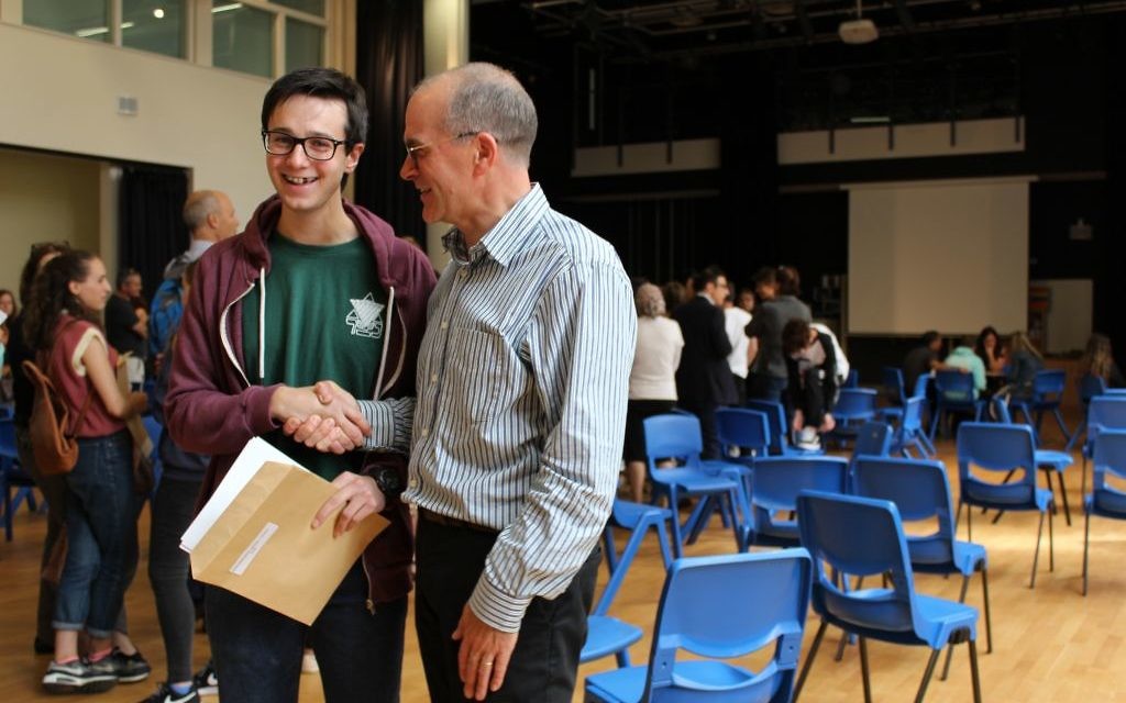 JCoSS headteacher shakes hands with a top performing student during August's A-Level results
