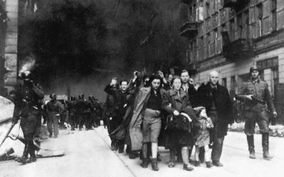 Captured Jews in the Warsaw Ghetto are led by German troops to the assembly point for deportation.