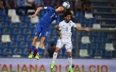 Italy's Andrea Conti heads the ball away, under pressure from Lior Raaelov