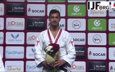 Tal Flicker on the podium with the International Judo Federation uniform, as he quietly sings Hatikvah