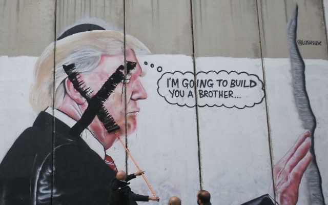 A Palestinian paints over a mural of the U.S. President Donald Trump during a protest in Bethlehem, West Bank,    (AP Photo/Nasser Shiyoukhi)