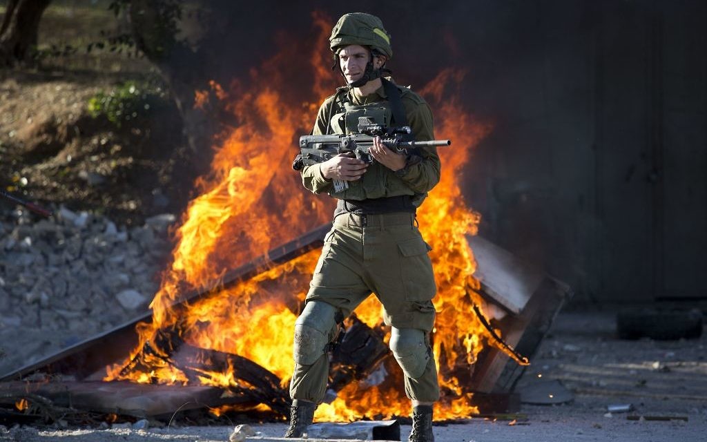 Israeli soldier stands during clashes with Palestinians following a protest against U.S. President Donald Trump's decision to recognize Jerusalem as the capital of Israel in the West Bank City of Nablus, Friday, Dec. 8, 2017. (AP Photo/Majdi Mohammed)