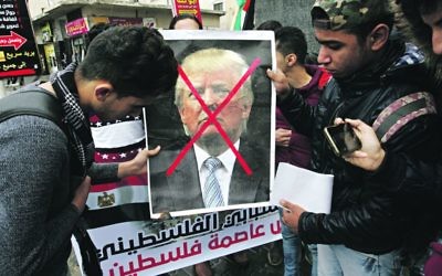 Arab protesters hold a sign with a picture of Donald Trump crossed out, in opposition to the President's move