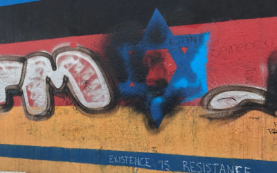 Graffiti on the Berlin Wall over a star of Davidm with the words 'existence is resistance '